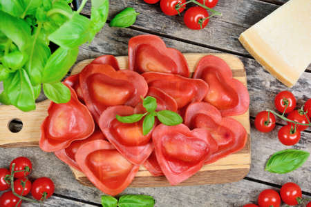 Red heart ravioli with cherry tomato, mozzarella, parmesan and basil close upの写真素材