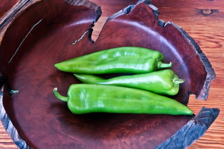 Serrano peppers in a burlwood bowl on a wood tableの写真素材