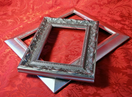 Silver Picture Frames stacked on a red brocade textileの写真素材