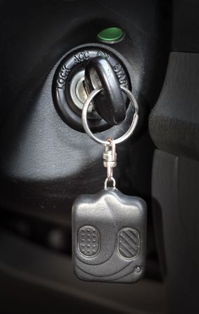 Automobile key with a charm inserted into the lock of ignition of the carの写真素材