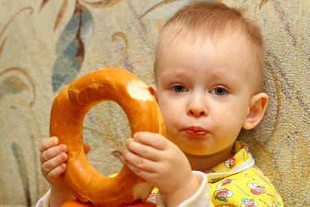 Little boy in yellow shirt who eats a bagelの写真素材