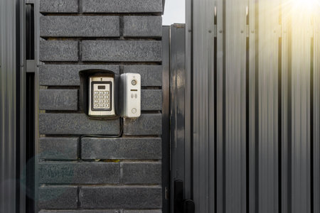 Intercom and security camera on the brick wall outside residential building.