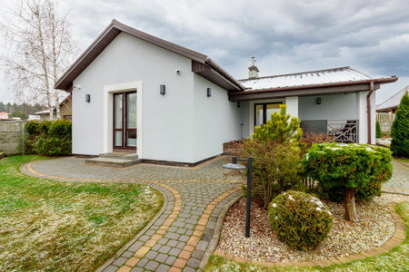 Guest house with green lawn and plants, with a small amount of snow fallingの写真素材