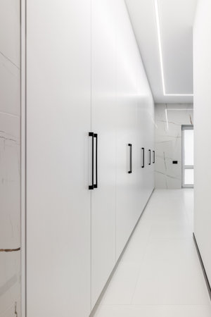 White long wardrobe from floor to ceiling. White doors with metal handles.の写真素材