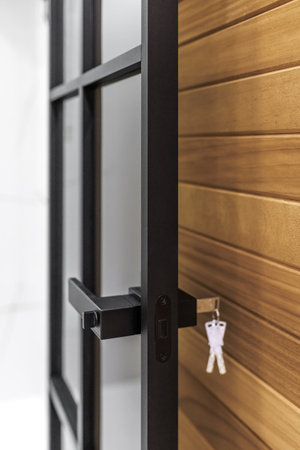 A modern black door with black handles and horizontal, cedar siding at the entrance to the house.