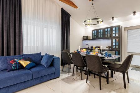 A modern living room with a blue sofa and a fixed table. Ceiling with wooden beams. open space.の写真素材