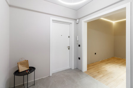Chrome handle with keyhole on white door with panels in frames. Entrance. Close-up photo of architecture detail.の写真素材