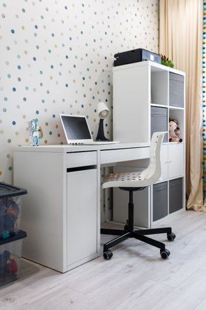 A workplace for a child with a table, a laptop and a table lamp in a modern apartment.の写真素材