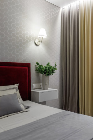 Bed with a blanket, pillows, sconces, bedside table - concept of a hotel room