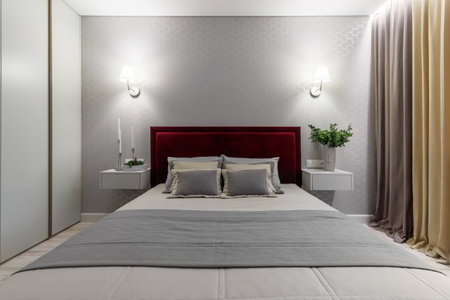 Modern bedroom with a bed with a burgundy heading and bedside tables.の写真素材