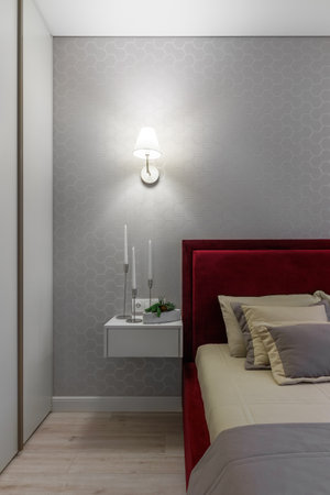 Modern bedroom with a bed with a burgundy heading and bedside tables.の写真素材