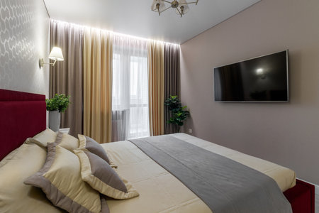 Modern bedroom with a bed with a burgundy heading and bedside tables.の写真素材