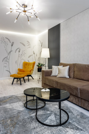 Modern interior design of a living room with a mustard chair, a floor lamp and personal accessories.