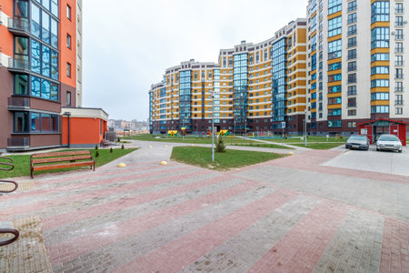 Children's playground in the courtyard of a multi-storey residential building against the background of a blue skyの写真素材