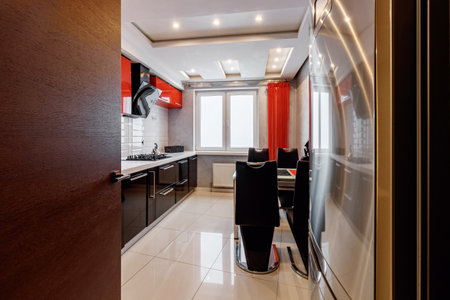 Modern kitchen interior with red and black cabinets and white ceramic floor.の写真素材