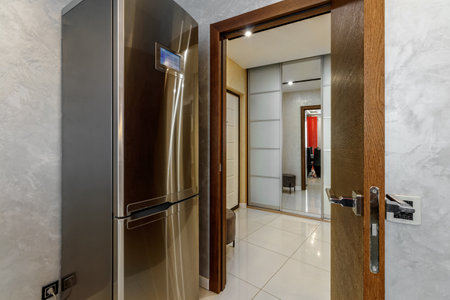 Stainless steel refrigerator with an electronic board with a view of another room.の写真素材