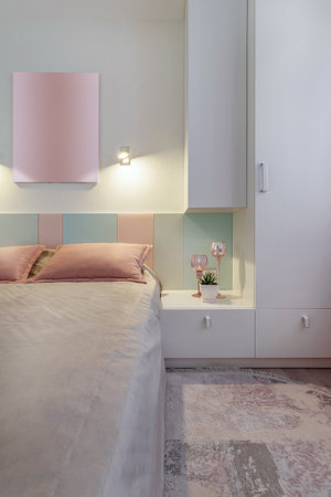 A modern bedroom in blue, pink and white colors with muffled lighting. real photo.の写真素材