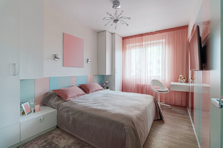 A modern bedroom in blue, pink and white colors with muffled lighting. real photo.の写真素材