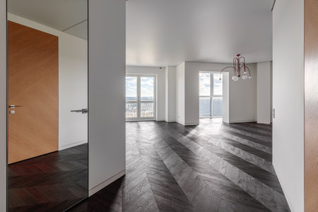 Empty room with dark wooden floating laminate flooring. House interior, wide bedroom or living room space. Newly recently painted new apartment or house. wood floor. Real estate or property management.の写真素材