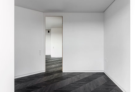 Empty room with dark wooden floating laminate flooring. House interior, wide bedroom or living room space. Newly recently painted new apartment or house. wood floor. Real estate or property management.の写真素材