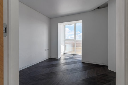 Empty apartment with large floor-to-floor window overlooking nature and blue sky with clouds.の写真素材