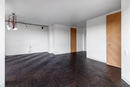 Empty room with dark wooden floating laminate flooring. House interior, wide bedroom or living room space. Newly recently painted new apartment or house. wood floor. Real estate or property management.の写真素材