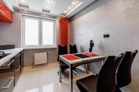 Modern kitchen interior with red and black cabinets and white ceramic floor.の写真素材