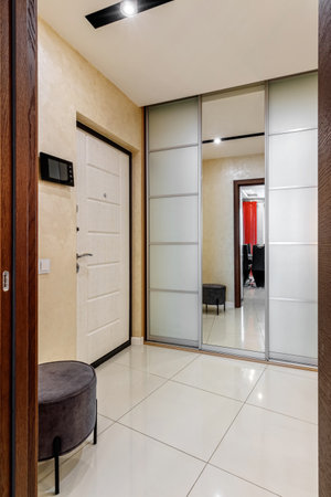 Entrance hall in the apartment with a large wardrobe with a mirror, soft pouf and other furniture.の写真素材