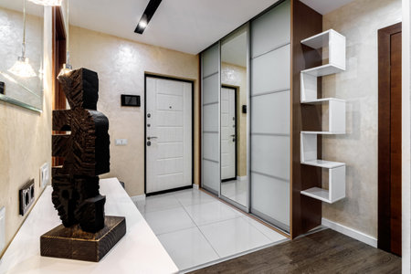 Entrance hall in the apartment with a large wardrobe with a mirror, soft pouf and other furniture.の写真素材