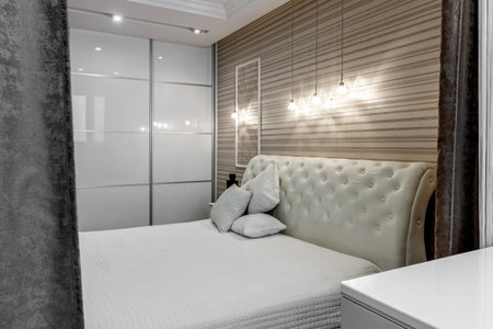 Bright bedroom with large white bed and capitone headboard.の写真素材