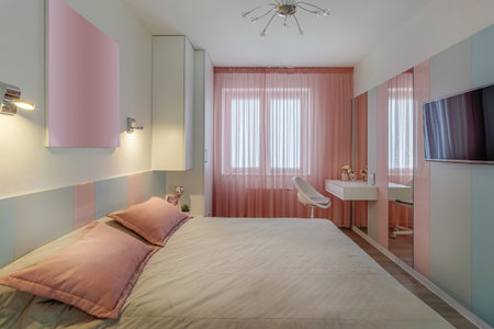 A modern bedroom in blue, pink and white colors with muffled lighting. real photo.の写真素材