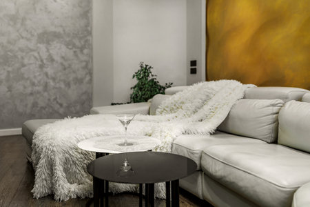 Living room with white walls and a huge white sofa, a black glossy wardrobe with a large yellow 3D panel on the wall.の写真素材