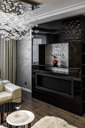 Black bio fireplace in the living room with large crystal chandelier in the apartment.の写真素材