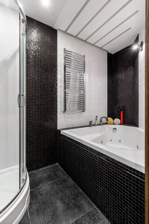 Bathroom with shower and large bathtub bathtub with contrasting white and black walls.の写真素材