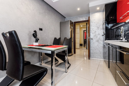Modern kitchen interior with red and black cabinets and white ceramic floorの写真素材