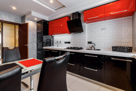 Modern kitchen interior with red and black cabinets and white ceramic floorの写真素材