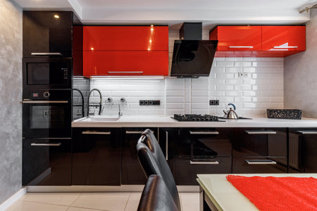 Modern kitchen interior with red and black cabinets and white ceramic floorの写真素材
