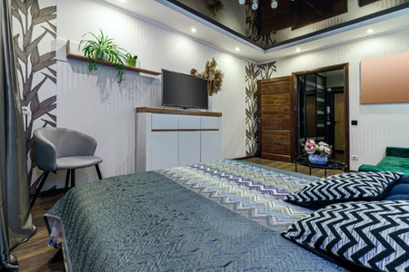 Modern room with bed, comfortable grey armchair and TVの写真素材