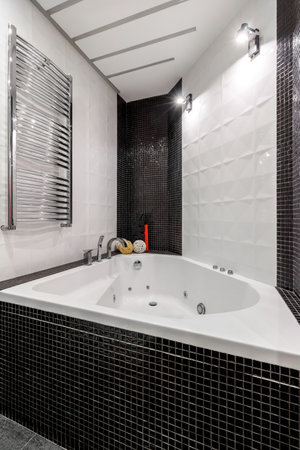 Bathroom with shower and large bathtub bathtub with contrasting white and black walls.の写真素材