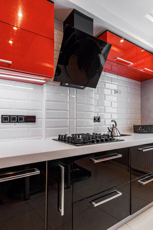 Modern kitchen interior with red and black cabinets and white ceramic floorの写真素材