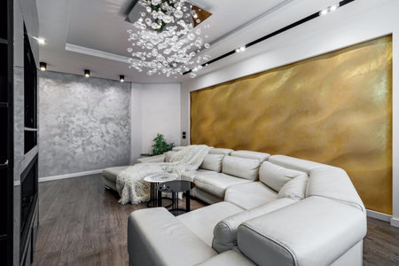 Living room with white walls and a huge white sofa, a black glossy wardrobe with a large yellow 3D panel on the wallの写真素材