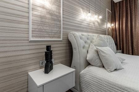 Bright bedroom with large white bed and capitone headboardの写真素材