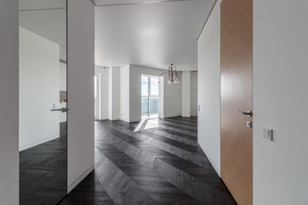 Empty room with dark wooden floating laminate flooring. House interior, wide bedroom or living room space. Newly recently painted new apartment or house. wood floor. Real estate or property management.の写真素材