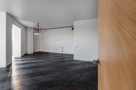 Empty room with dark wooden floating laminate flooring. House interior, wide bedroom or living room space. Newly recently painted new apartment or house. wood floor. Real estate or property management.の写真素材