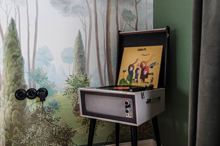 Turntable of vinyl records, stylized as a retro style standing on the floor in the room with an ABBA plate.の写真素材