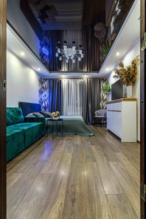 Modern interior of the room with bed, green sofa, black glossy ceiling.の写真素材