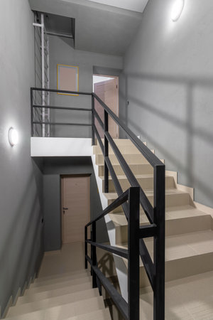 stairs made of tiles in a new house. metal black railing with wooden handrails Metal black railing, entrance to the apartment.の写真素材