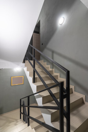 stairs made of tiles in a new house. metal black railing with wooden handrails Metal black railing, entrance to the apartment.の写真素材