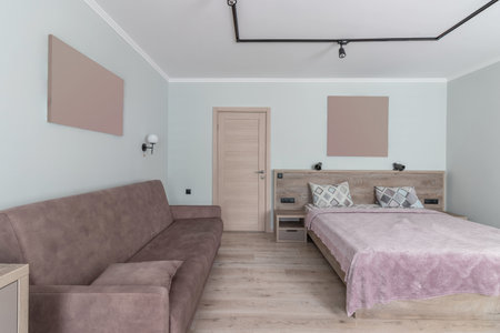 Hotel room with a large double bed in light colors.の写真素材