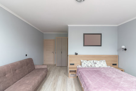 Hotel room with a large double bed in light colors.の写真素材